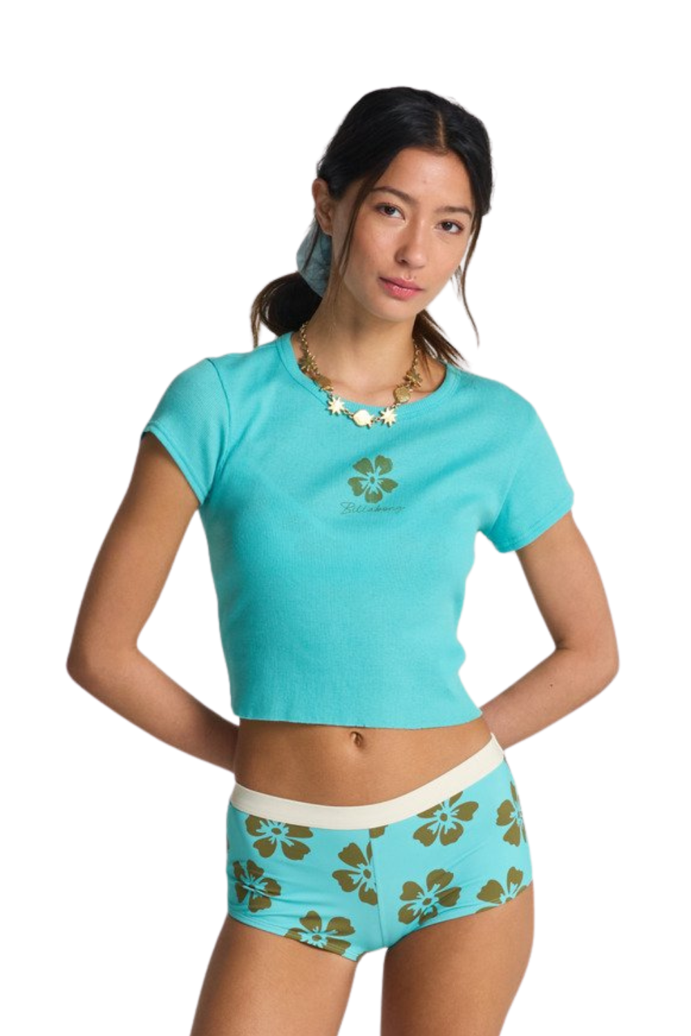 Woman wearing a turquoise cropped t-shirt with a small flower print on the chest