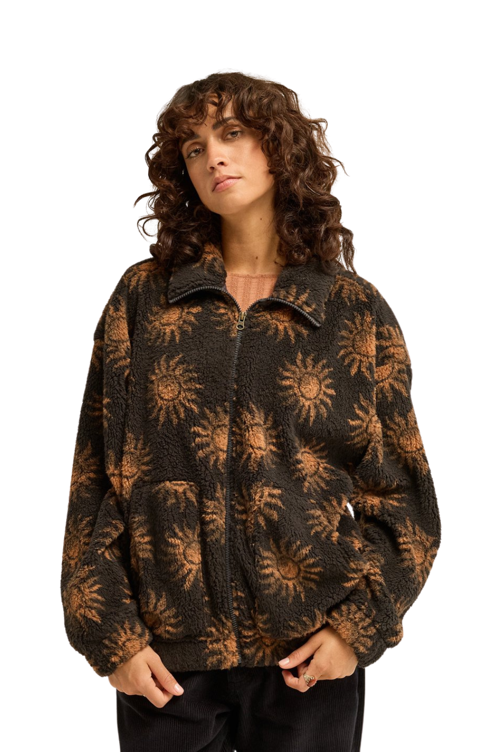 A woman wearing a dark brown fleece jacket with a tan sunburst pattern, photographed against a solid white background.