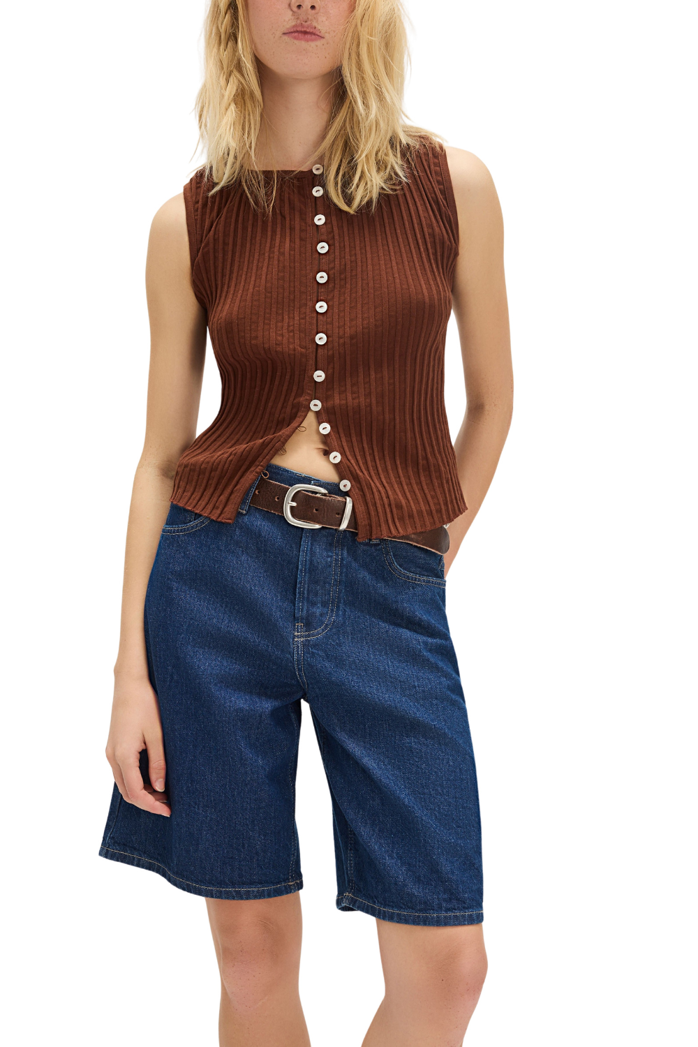 Woman wearing a brown ribbed knit sleeveless top and blue denim shorts on a white background