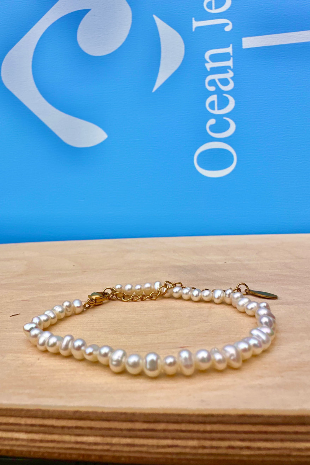Pearl bracelet on a wooden surface with a blue background