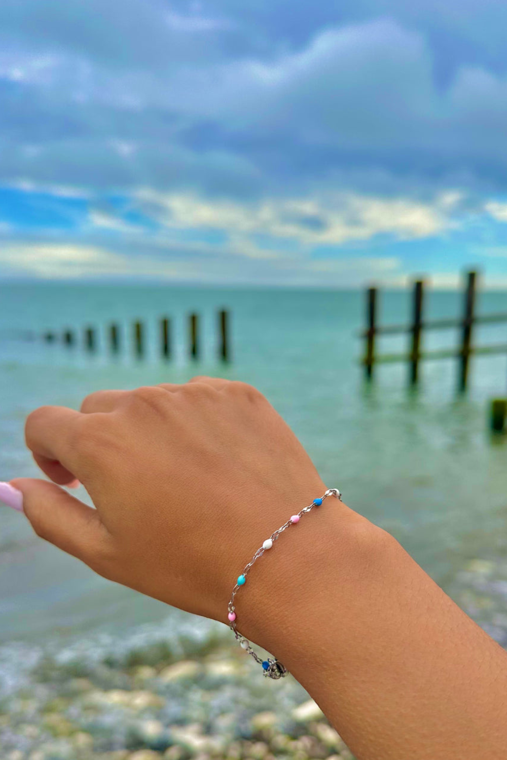 Hand wearing a bracelet with small enamel beads in different colours.