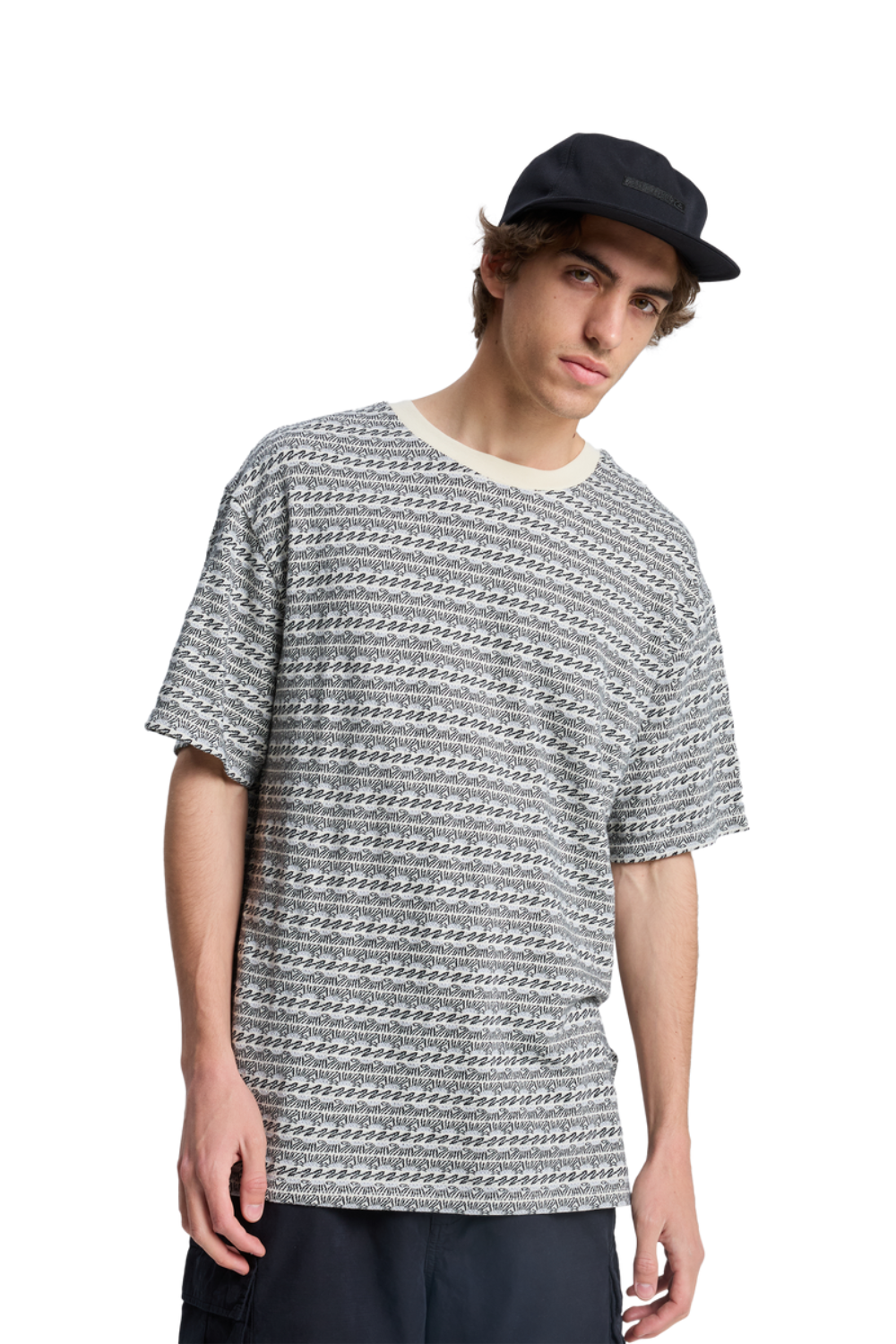 Person wearing a patterned t-shirt and black cap on a white background