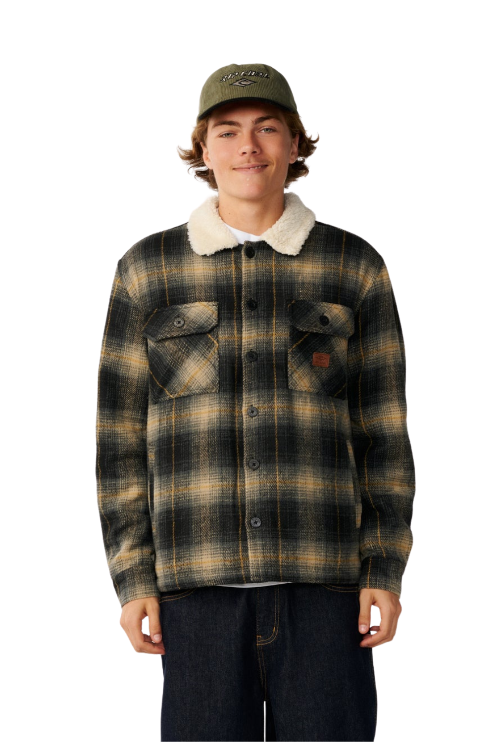 A young man wearing a brown and black plaid flannel jacket with a white sherpa collar, dark jeans, and an olive green baseball cap, standing against a solid white background.