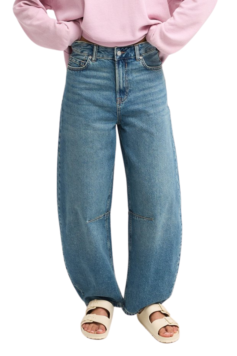 A person wearing high-waisted, wide-leg blue denim jeans with a pink sweatshirt and beige slide sandals, shown from the waist down on a white background.
