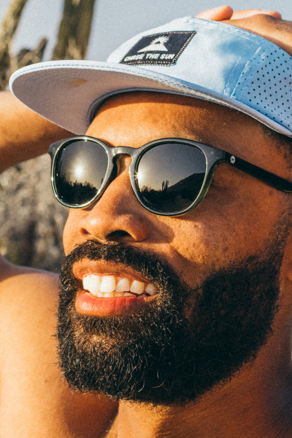 Man wearing sunglasses and a cap outdoors.