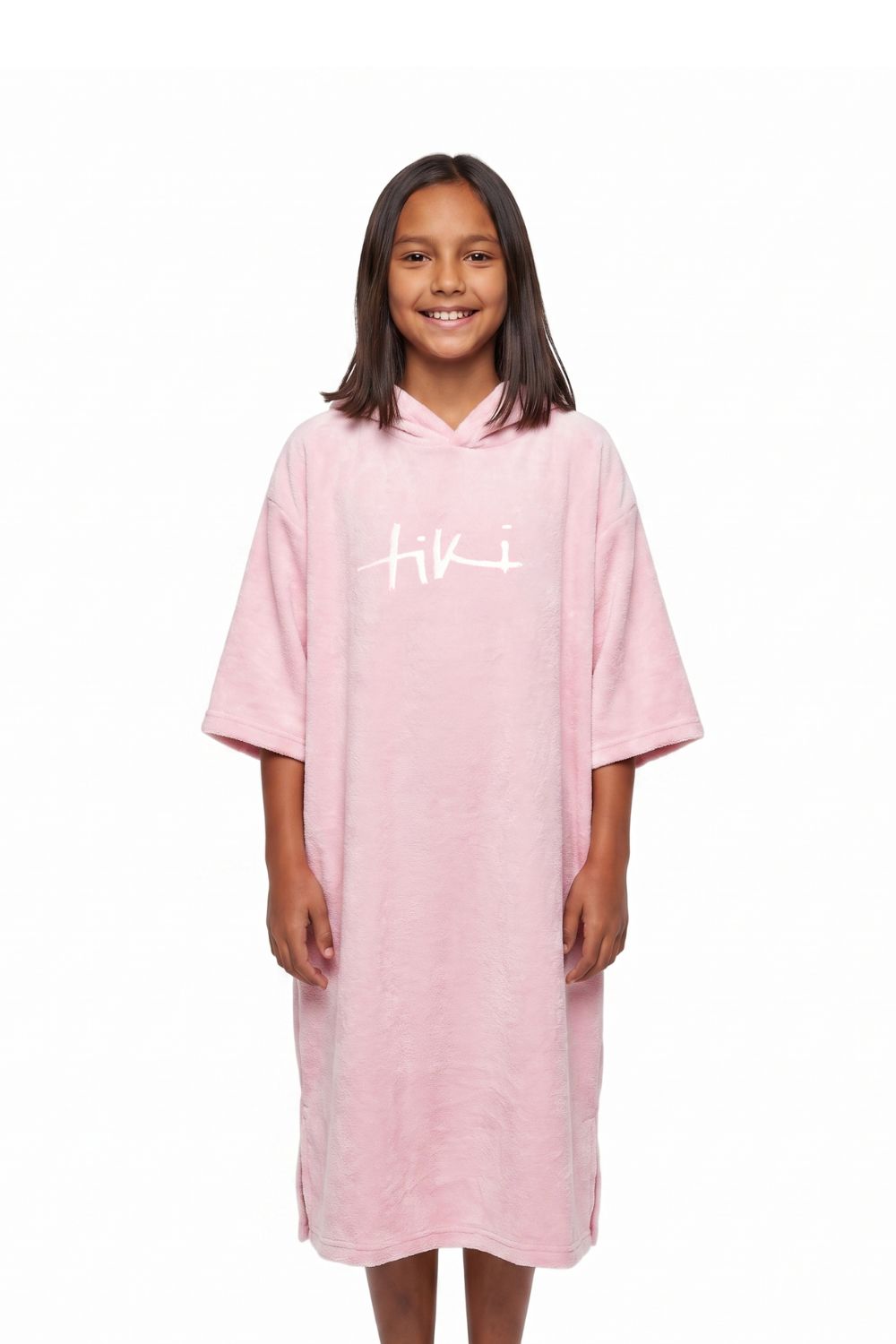 A young girl with shoulder-length dark hair stands against a plain white background wearing a light pink hooded towel dress with a white 'hiki' logo printed on the chest.