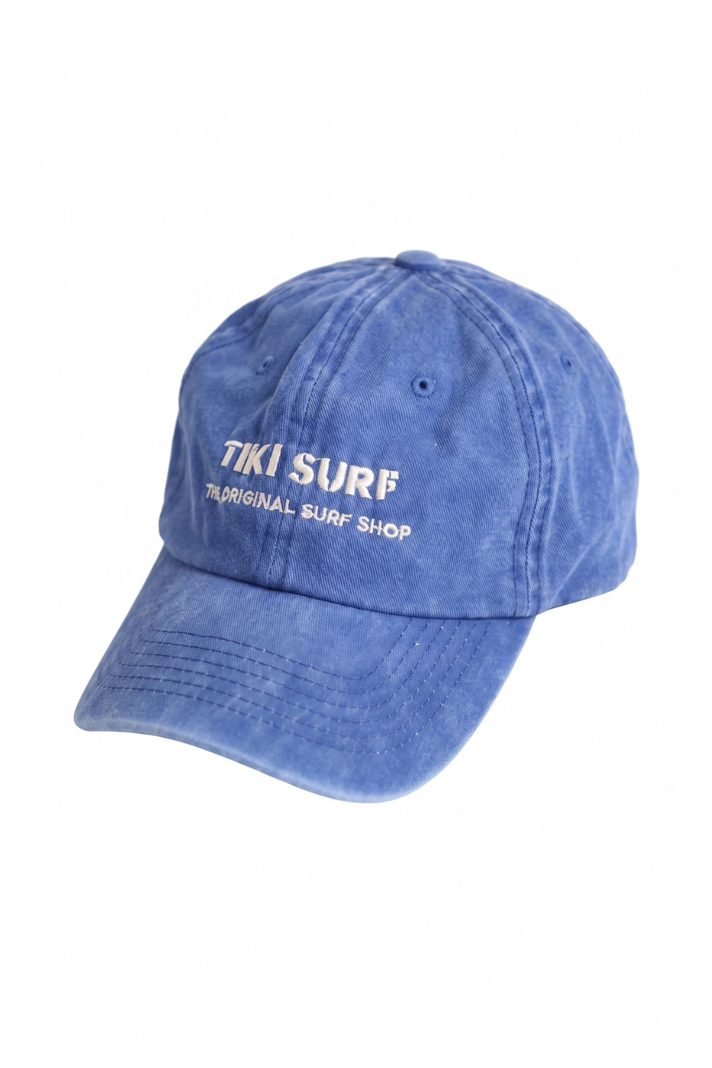 A blue washed cotton baseball cap with white embroidered text reading 'Tiki Surf' and 'The Original Surf Shop' on the front, shown against a plain white background.