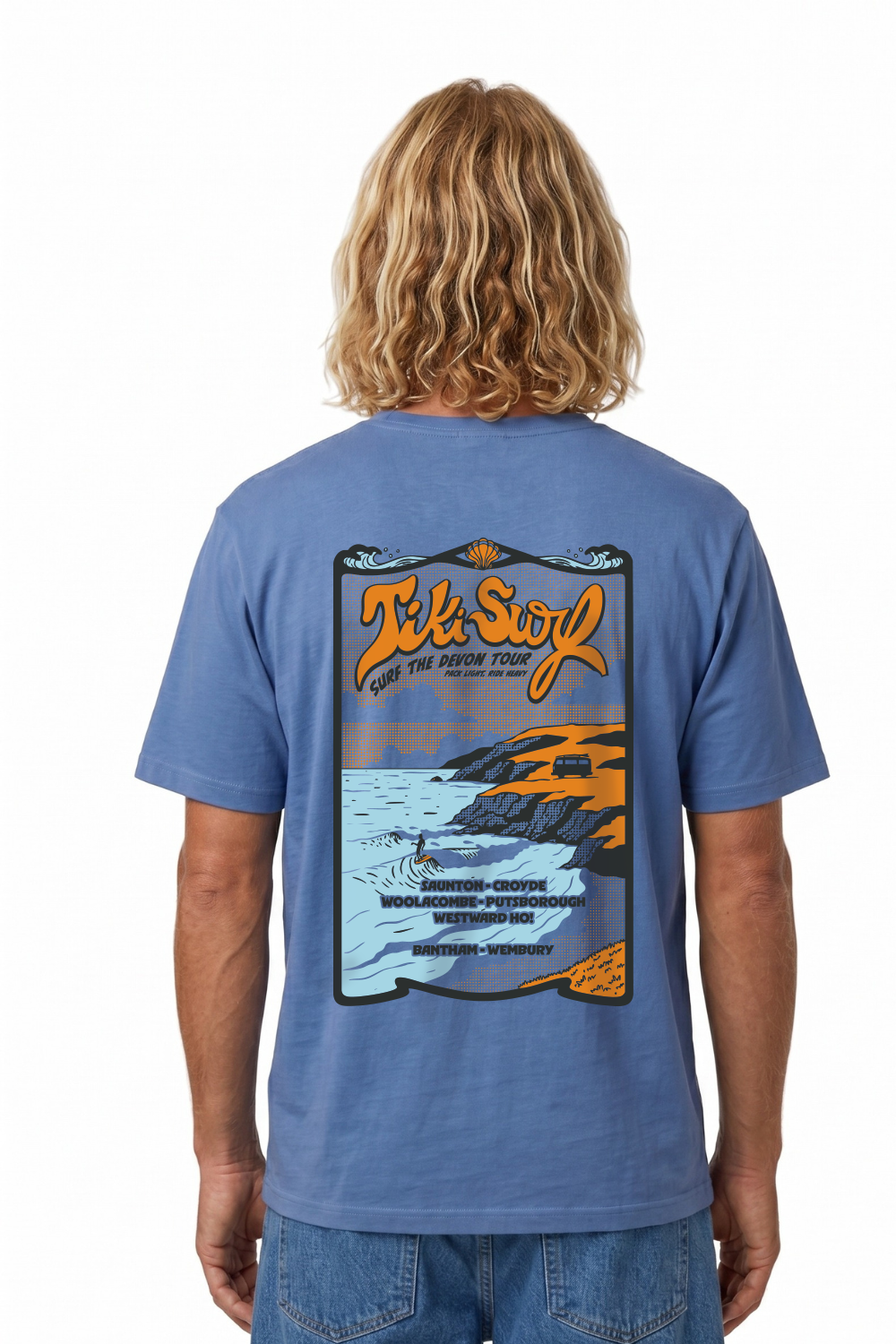 Person wearing a Tiki T-Shirt in bright blue. Featuring a bold retro back print showcasing Devon’s famous surf beaches.