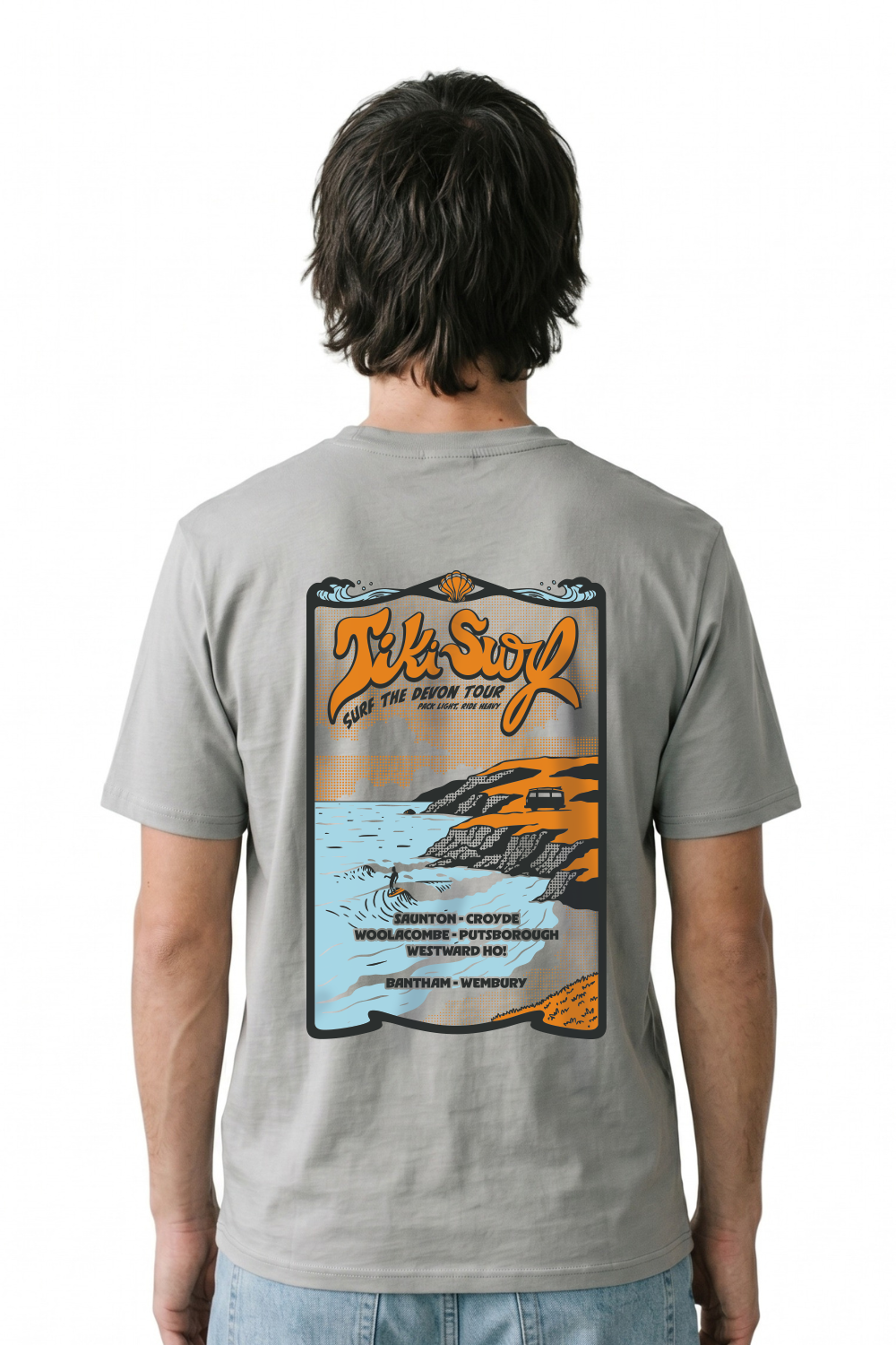 Person wearing a Tiki T-Shirt in bright blue. Featuring a bold retro back print showcasing Devon’s famous surf beaches.