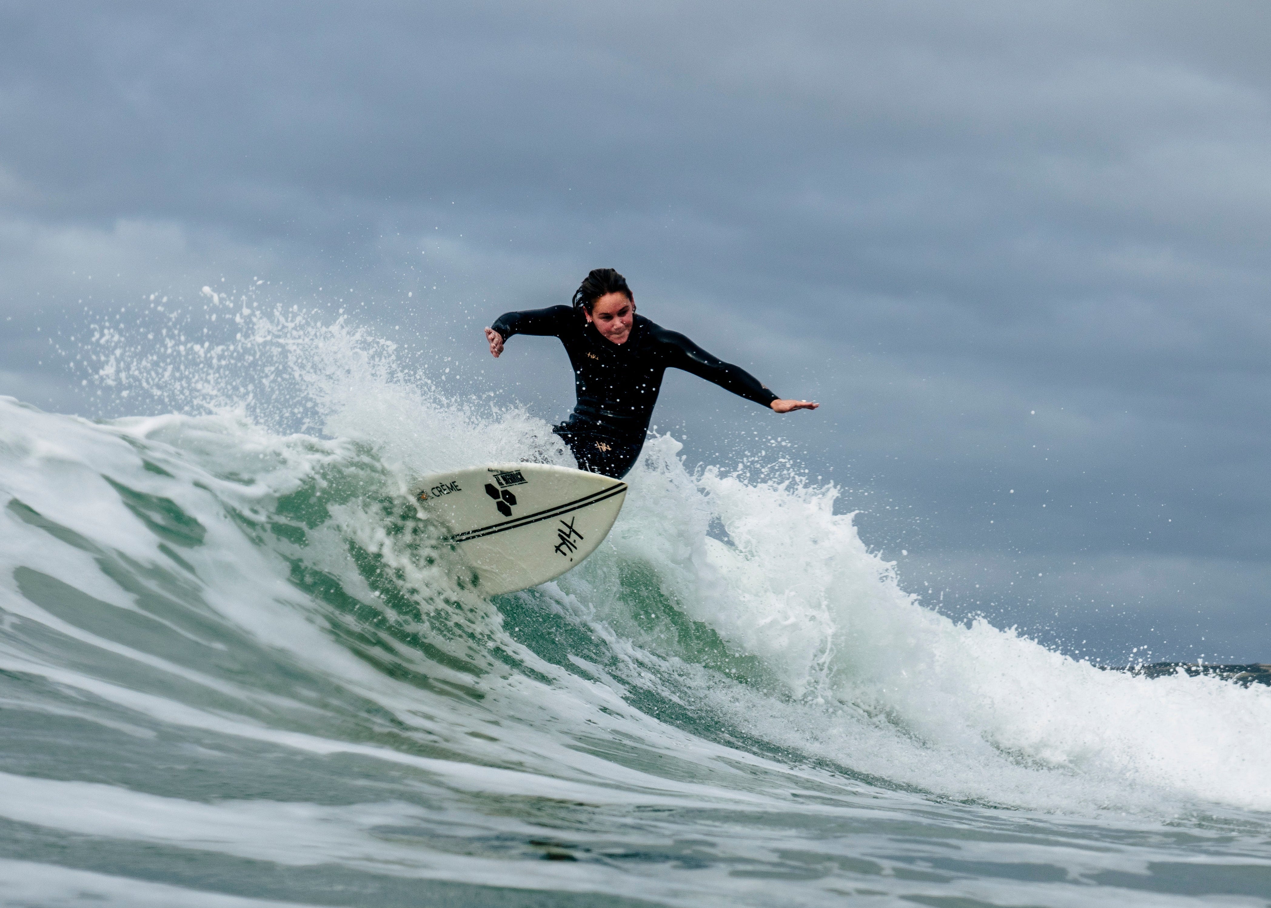 performance woman female surfer in uk sea in new wetsuit on surfboard