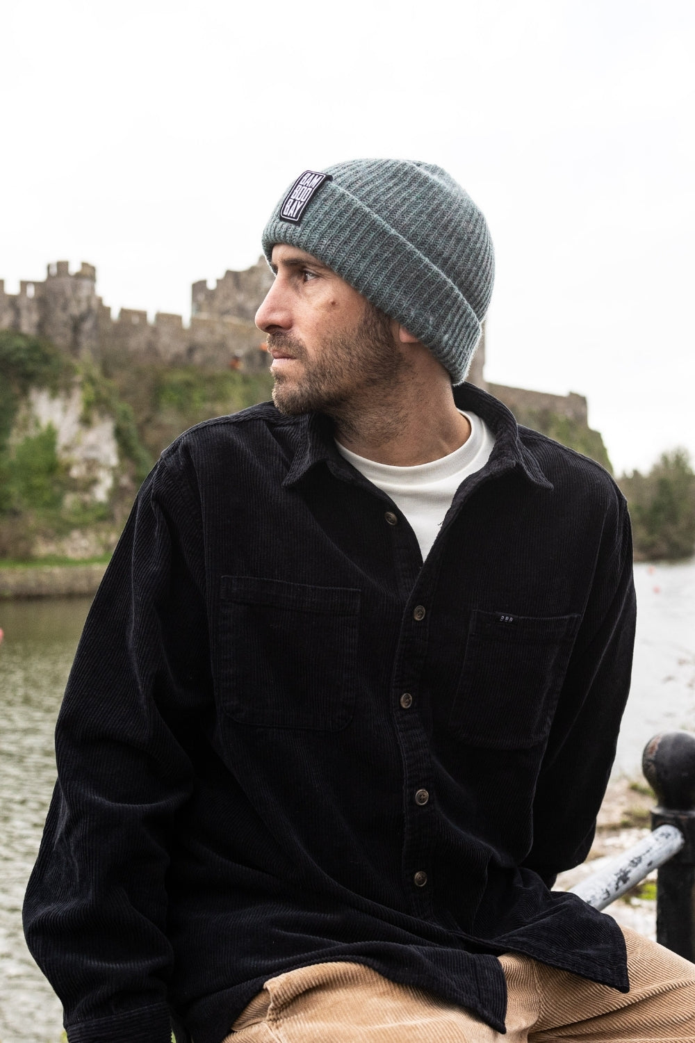 Man wearing a gray beanie and black shirt with a castle in the background