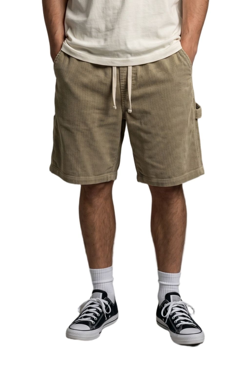 Person wearing beige corduroy shorts and black sneakers on a white background
