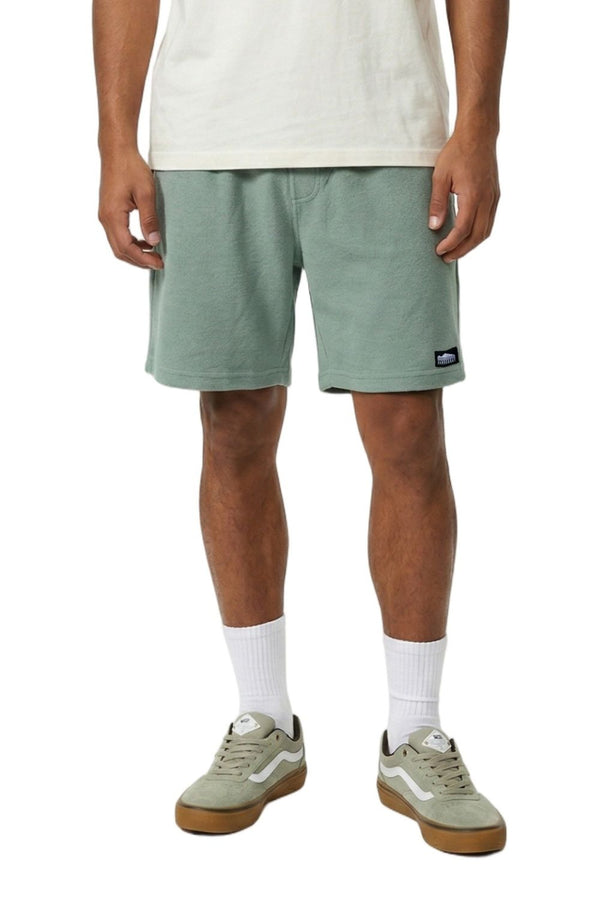 Person wearing green shorts and white socks on a white background