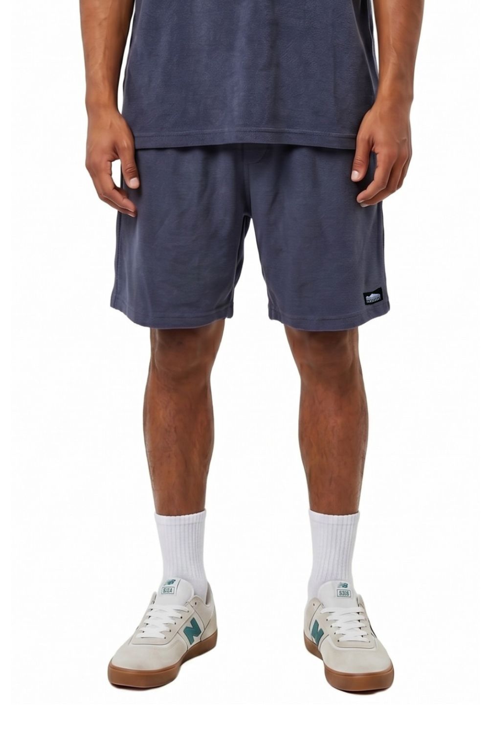 Person wearing navy shorts and white sneakers on a white background