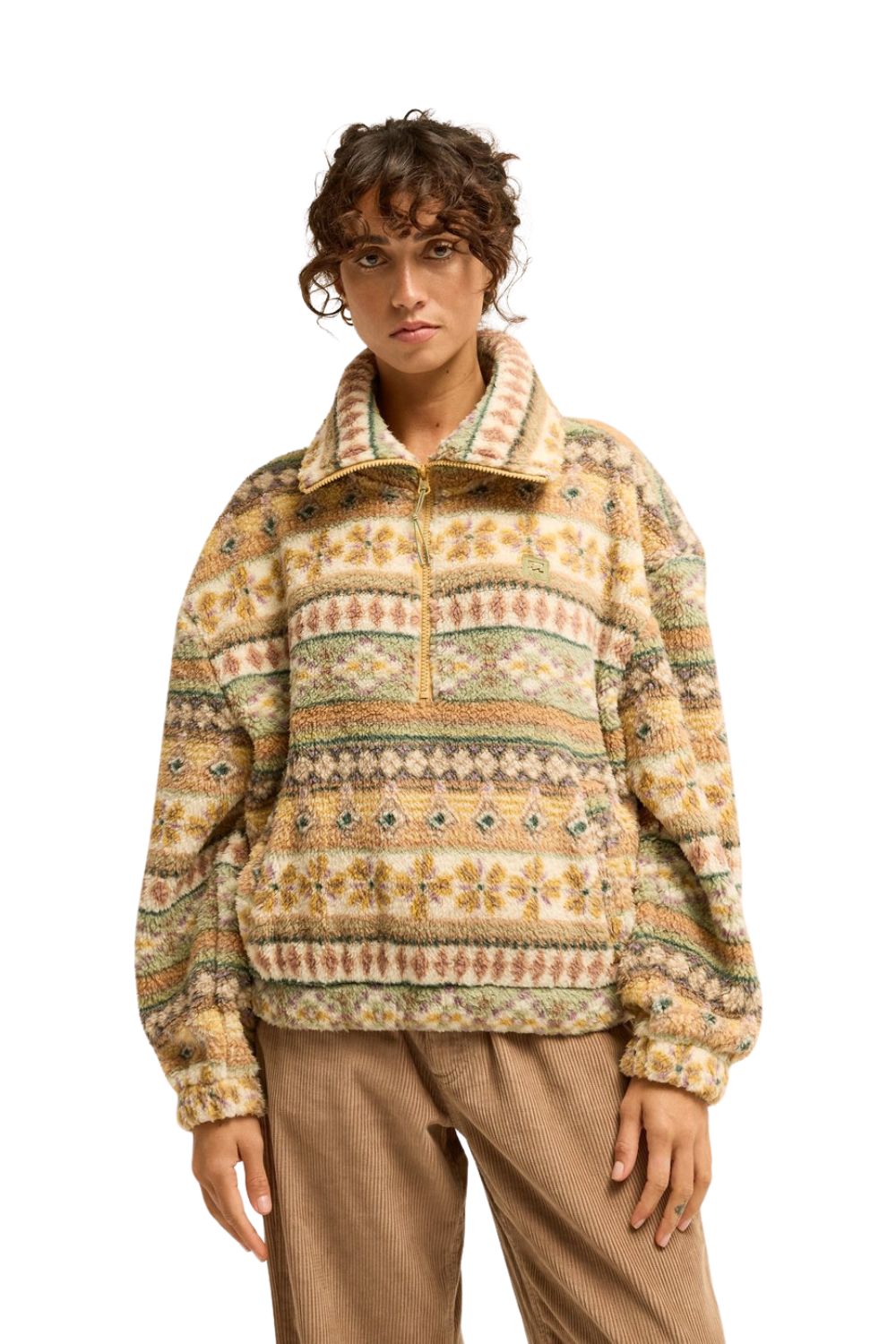 A model wearing a Billabong quarter-zip fleece pullover fleece with a colorful geometric Fair Isle pattern in beige, brown, green, and orange, paired with brown pants, against a solid white background.