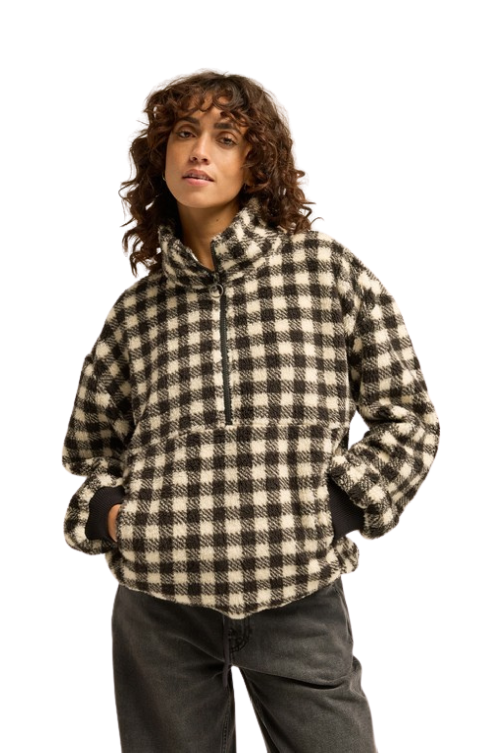 A woman wearing a black and beige buffalo check fleece pullover hoodie with a half-zip and high collar, paired with dark gray jeans, against a solid white background.