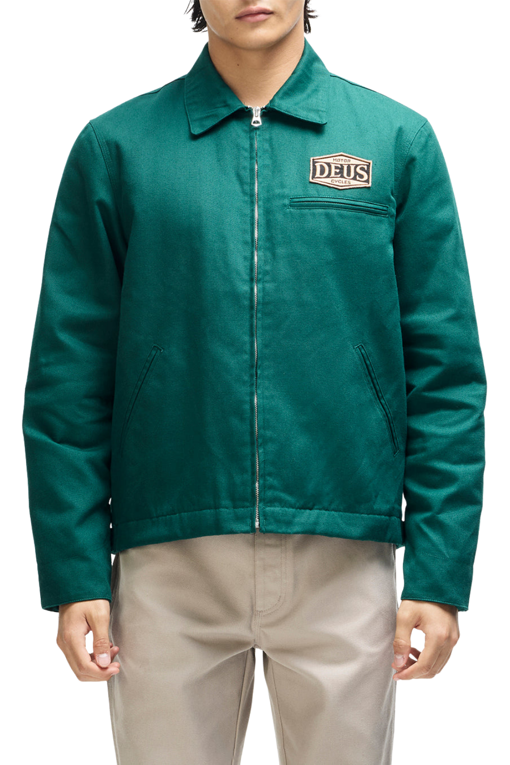 A man wearing a teal green Daus work jacket with a zip-up front and a brand patch on the chest, paired with beige pants, against a plain white background.