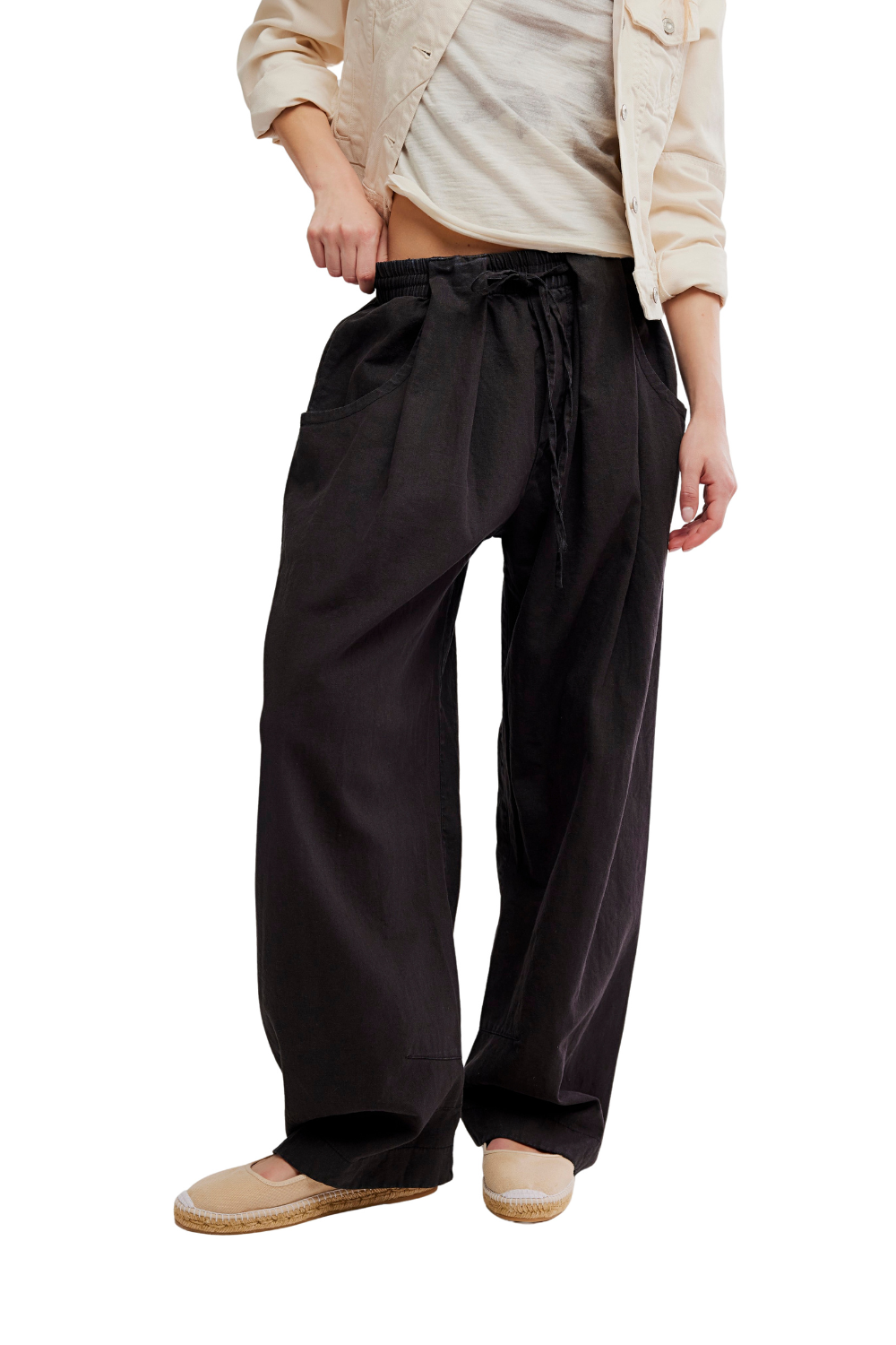 Person wearing black wide-leg pants with a beige shirt on a white background