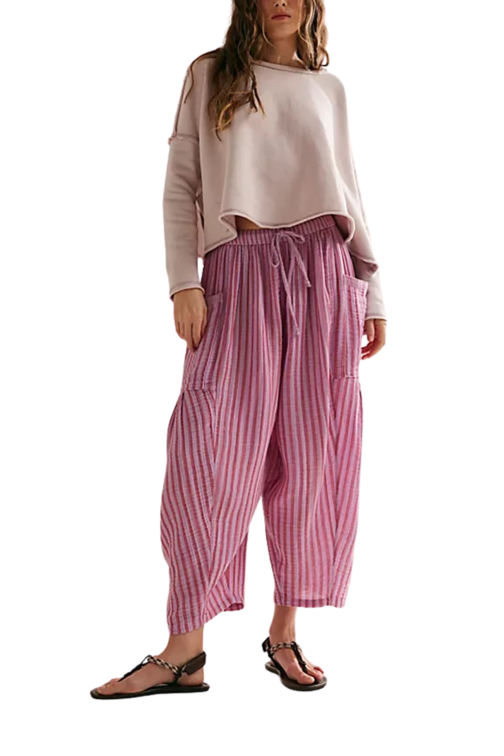 Woman wearing a light pink top and pink striped pants on a white background