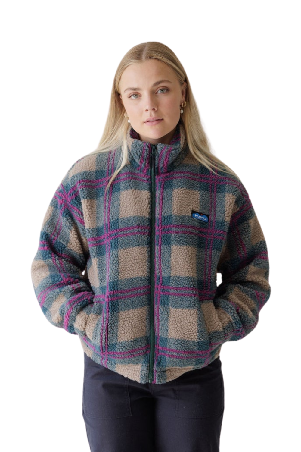 A woman modeling a Kavu fleece jacket with a blue, beige, and pink plaid pattern, paired with dark pants, against a plain white background.