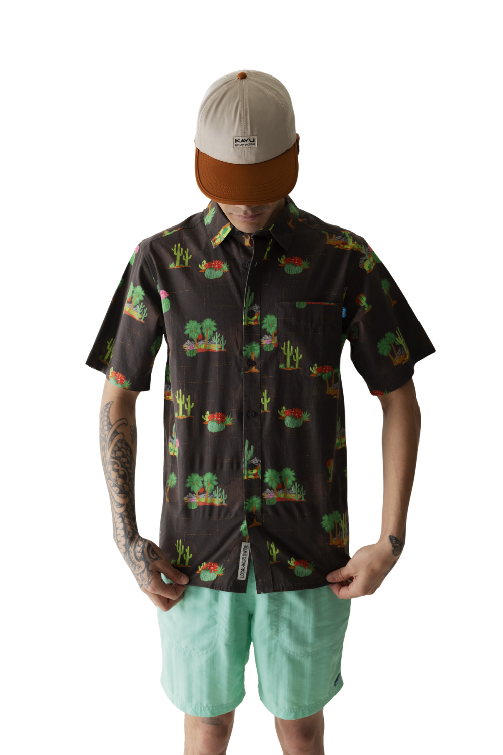 Person wearing a patterned shirt and light green shorts on a white background