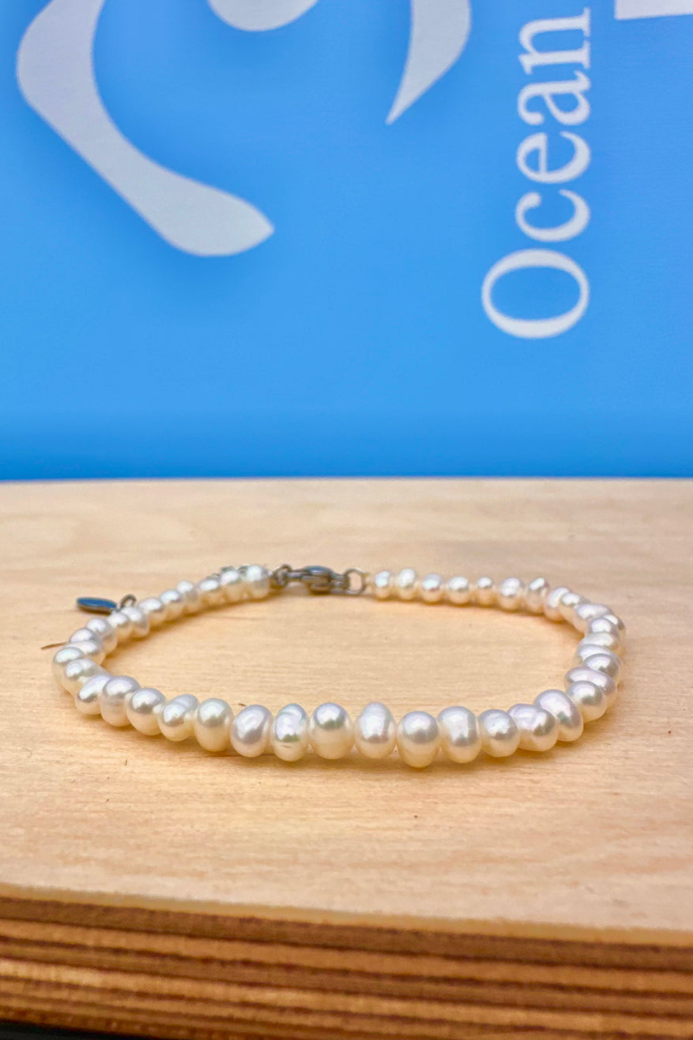 Pearl bracelet on a wooden surface with a blue background