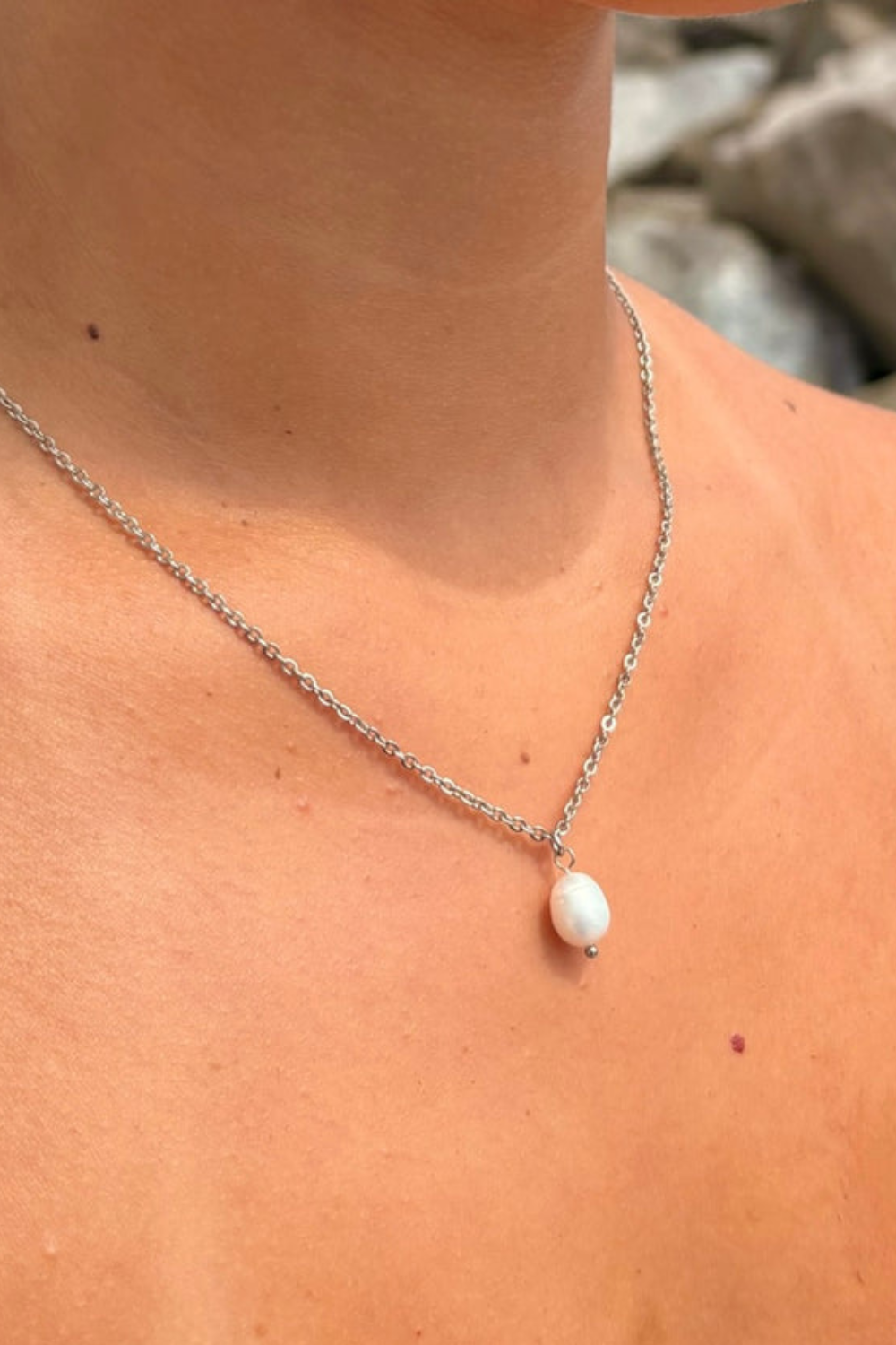 Pearl pendant silver necklace on a person's neck 