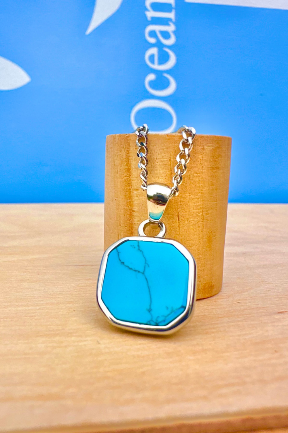 Silver necklace with al turquoise stone pendant on a wooden stand