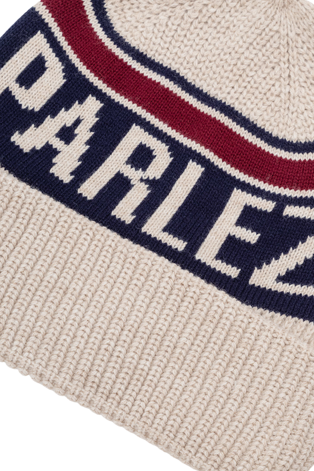 Close-up of a ribbed knit beanie in cream with a navy blue band featuring the word 'PARLEZ' in cream and a red stripe above it.