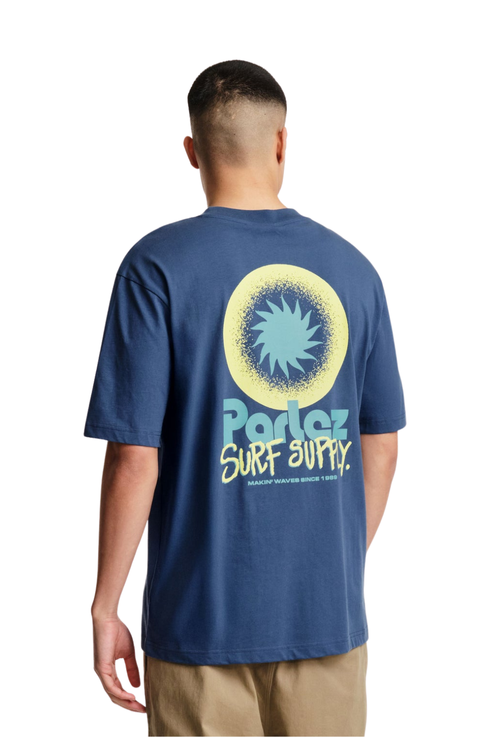 Person wearing a blue t-shirt with a logo and text on the back, on a white background