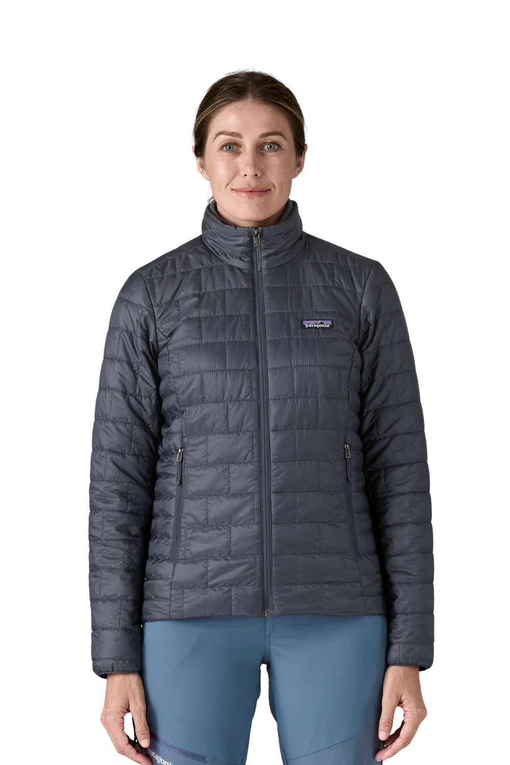 A woman modeling a dark gray quilted Patagonia jacket with a full-zip front and stand-up collar, paired with slate blue leggings, against a plain white background.