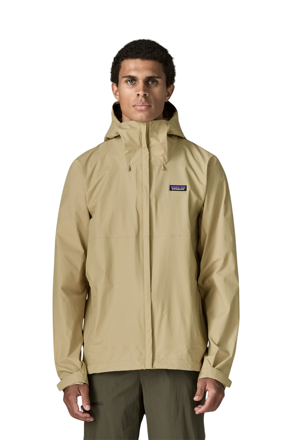 A man wearing a beige Patagonia hooded rain jacket and olive green pants, standing against a plain white background.