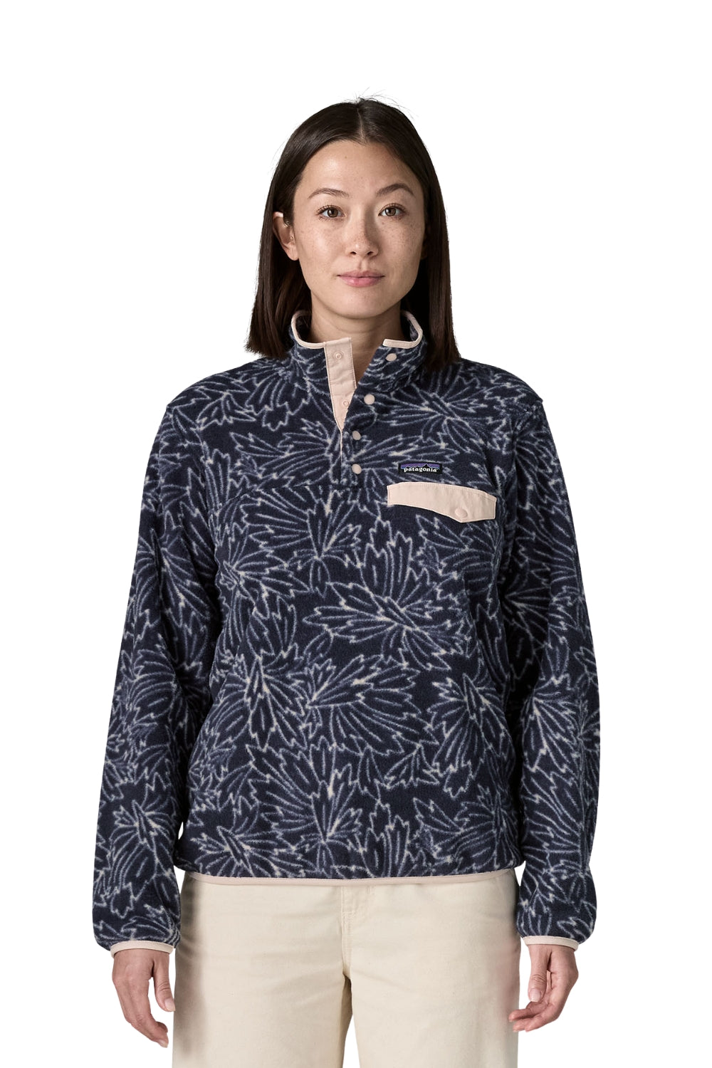 A woman modeling a navy blue quarter-zip fleece jacket with a white floral branch pattern and a beige chest pocket, paired with beige pants, against a plain white background.