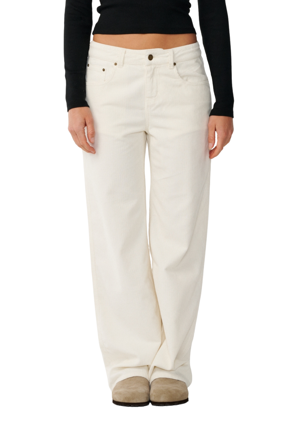 A person wearing off-white wide-leg cord trousers with a black long-sleeve crop top and beige slip-on shoes, shown from the waist down against a plain white background.