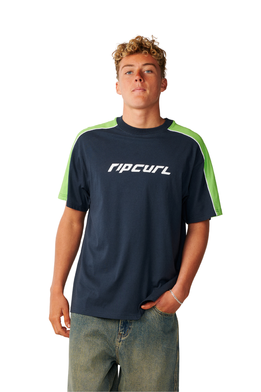 A young man wearing a navy blue Rip Curl t-shirt with bright green shoulder panels and a white logo on the chest, paired with blue jeans, against a plain white background.