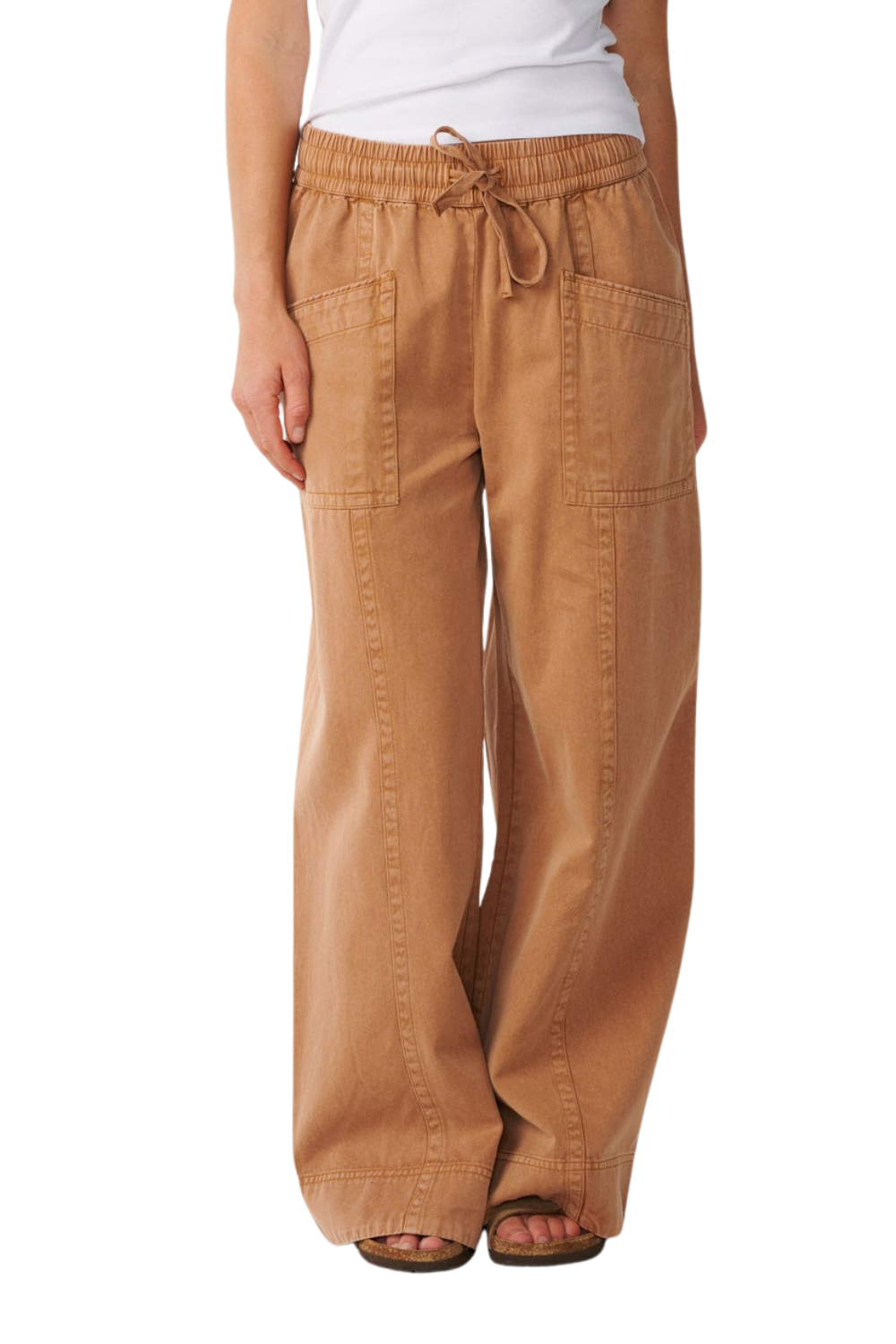 A person wearing wide-leg tan pants with an elastic drawstring waistband, shown from the waist down against a plain white background.