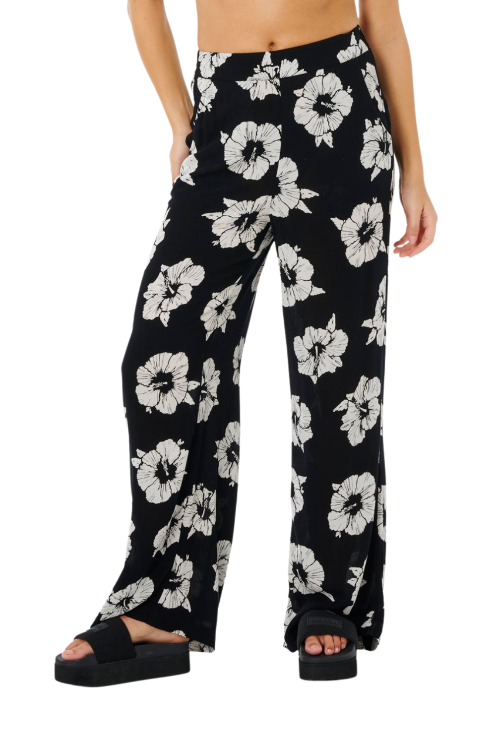 Black floral-patterned pants worn by a person on a white background
