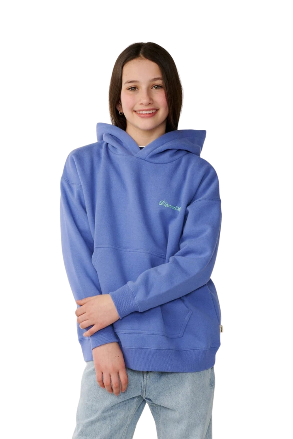 A young woman wearing a medium blue pullover hoodie with a small green embroidered logo on the left chest, paired with light wash jeans, photographed against a solid white background.