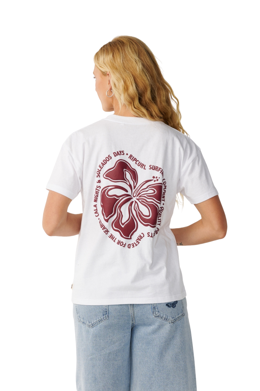 A woman shown from the back wearing a white short-sleeve T-shirt with a large maroon hibiscus flower graphic and circular text on the back, paired with light blue jeans, against a plain white studio background.