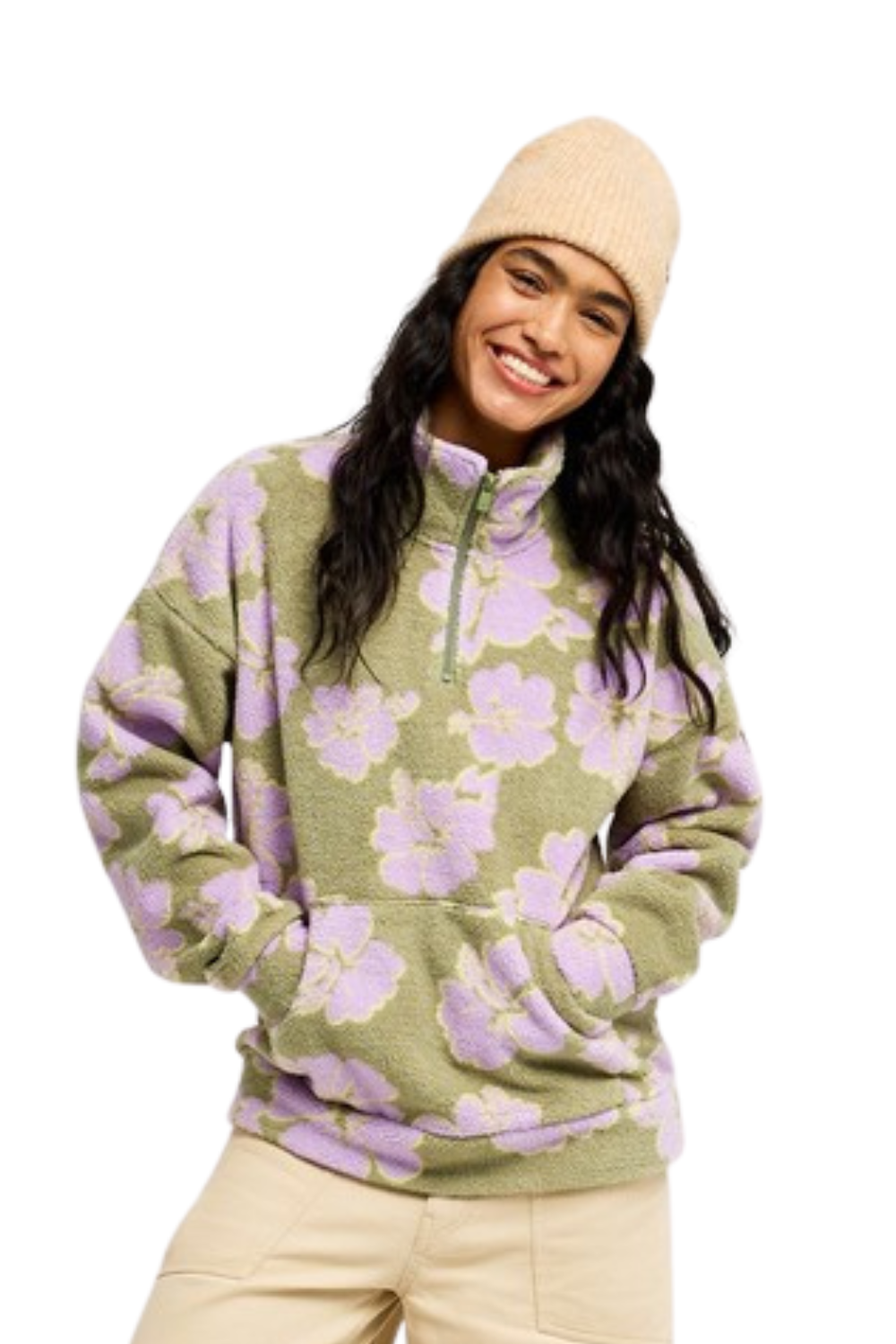 A woman wearing a fuzzy Roxy quarter-zip fleece pullover with a sage green and lavender floral pattern, paired with a beige knit beanie and light beige pants, set against a plain white background.