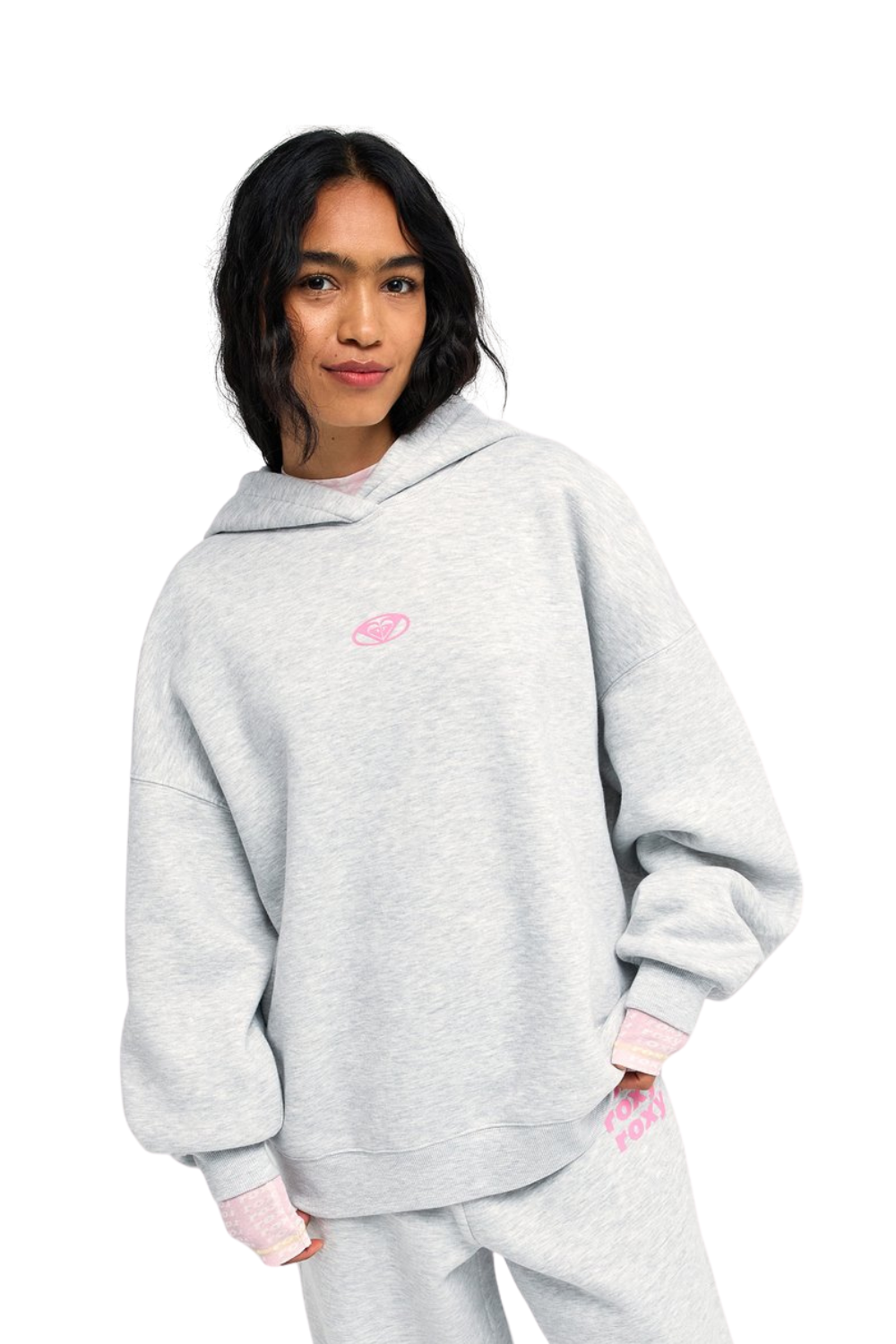 A model wearing a light gray heathered Roxy hoodie sweatshirt with a small pink Roxy heart graphic logo on the chest, paired with matching sweatpants against a solid white background.