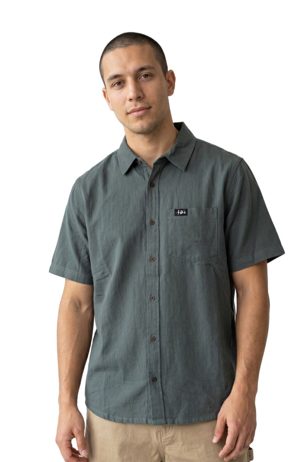 Man wearing a gray button-up short sleeve shirt with a Tiki logo on a white background