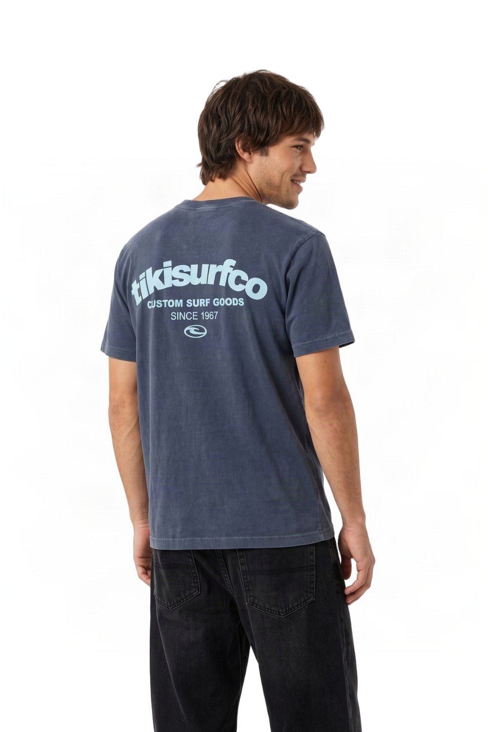 A man wearing a faded navy blue t-shirt with a large white 'Tkisurfco' logo printed on the back, shown from a three-quarters back view against a white background.