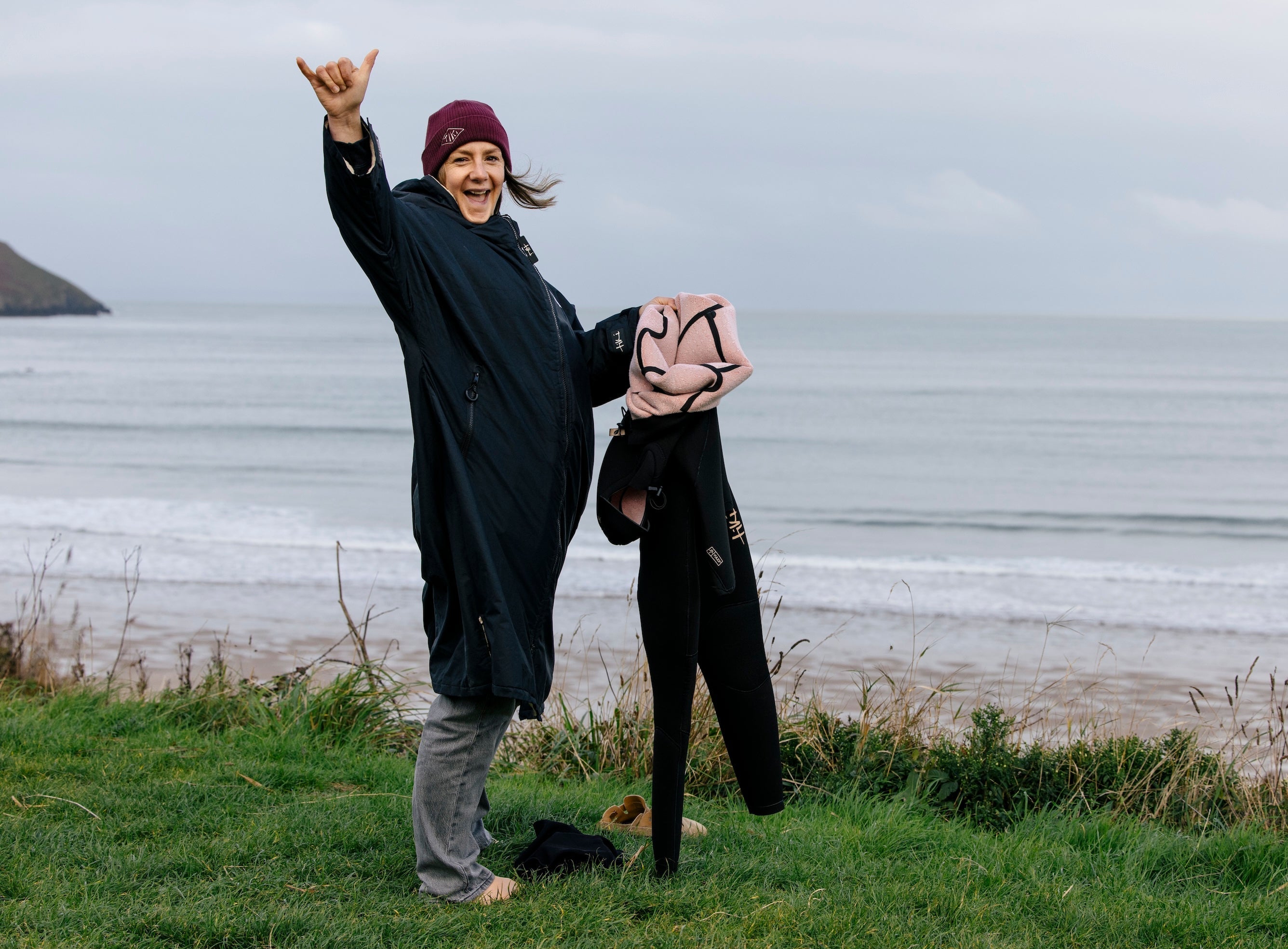female surfer holding a winter wetsuit