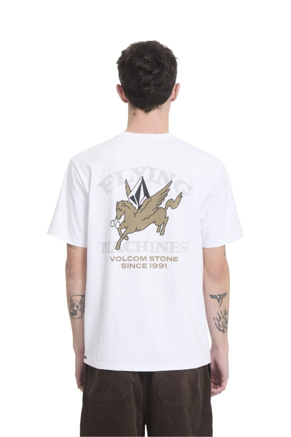 A man viewed from behind wearing a white t-shirt with a large graphic on the back. The graphic features a beige winged horse (Pegasus) and the text 'FLYING MACHINES VOLCOM STONE SINCE 1991'.