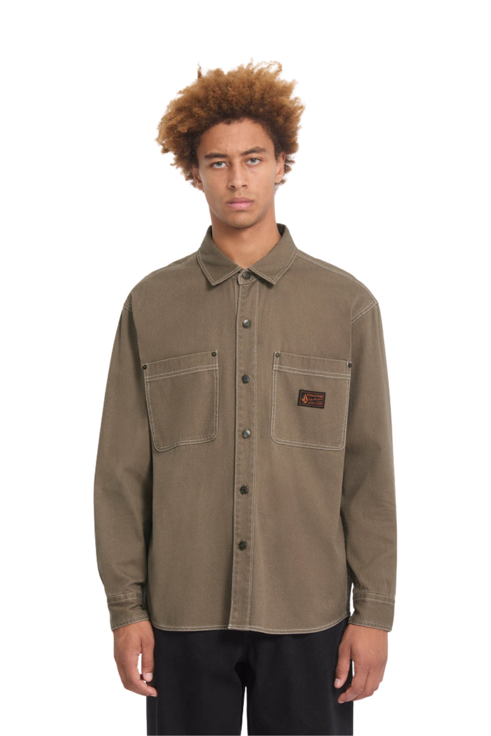 Man wearing a brown shirt with a Volcom label on the chest pocket.