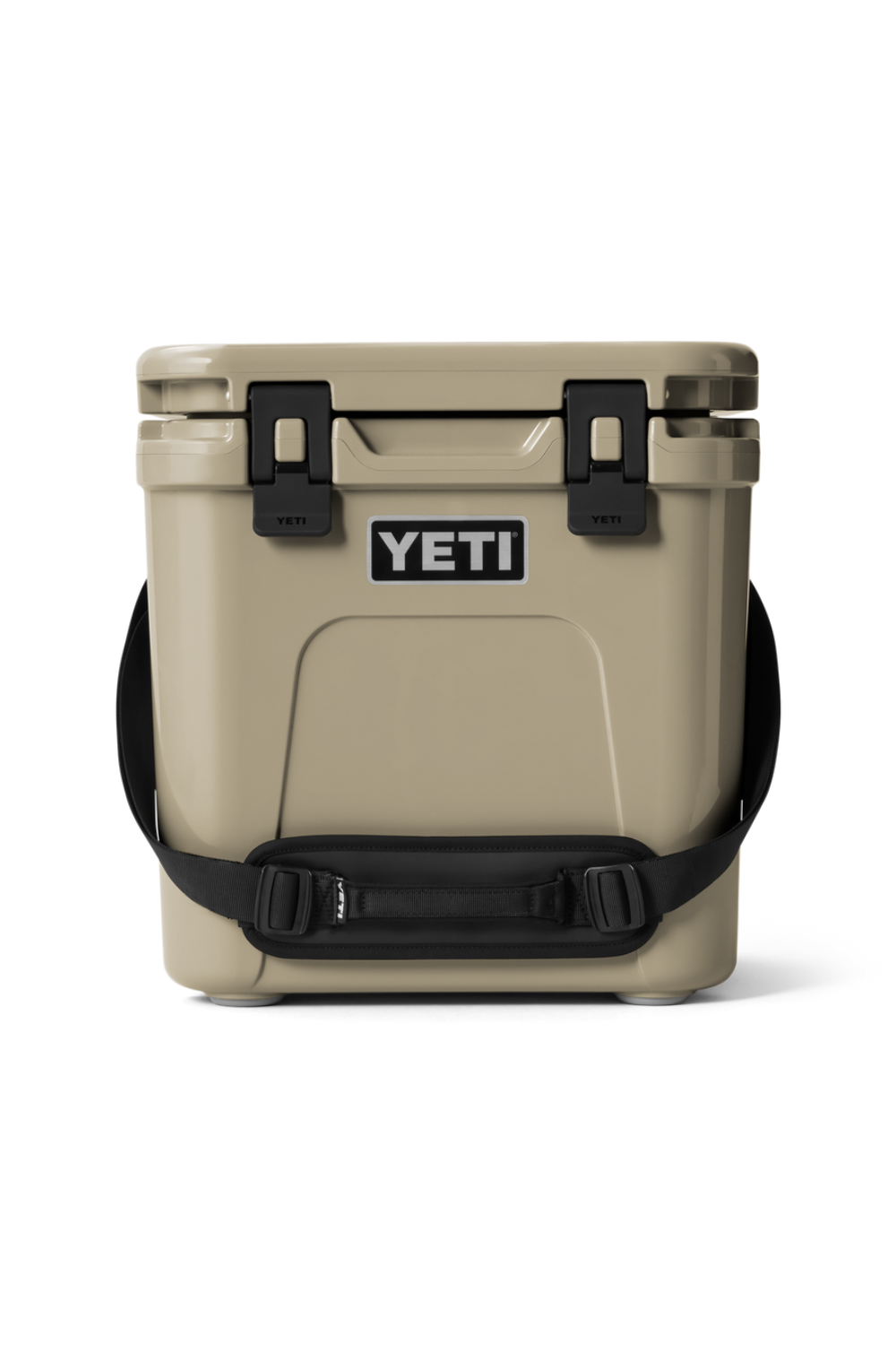 A YETI cooler in sand beige with black latches, a black shoulder strap, and a black handle, shown from the front on a white background.