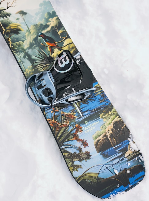 Snowboard with a nature-themed design on a snowy surface