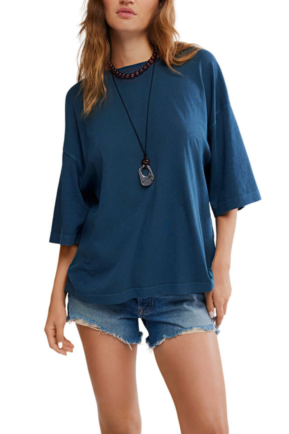 Woman wearing a blue oversized shirt and denim shorts on a white background